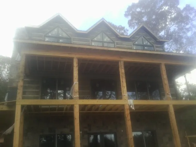 Dormers and porch framing on a large log home under construction — Roof Coating work by our crew in Winona