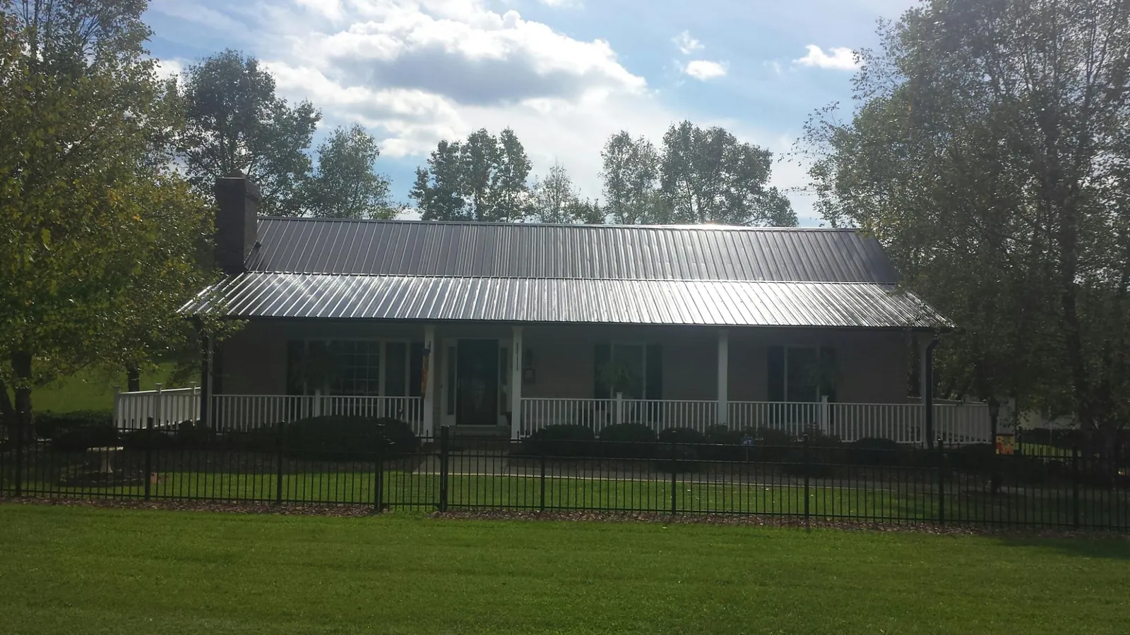 Gray metal roof on a brick ranch with a full width front porch — Gutter Guard Installation work by our crew in Winona