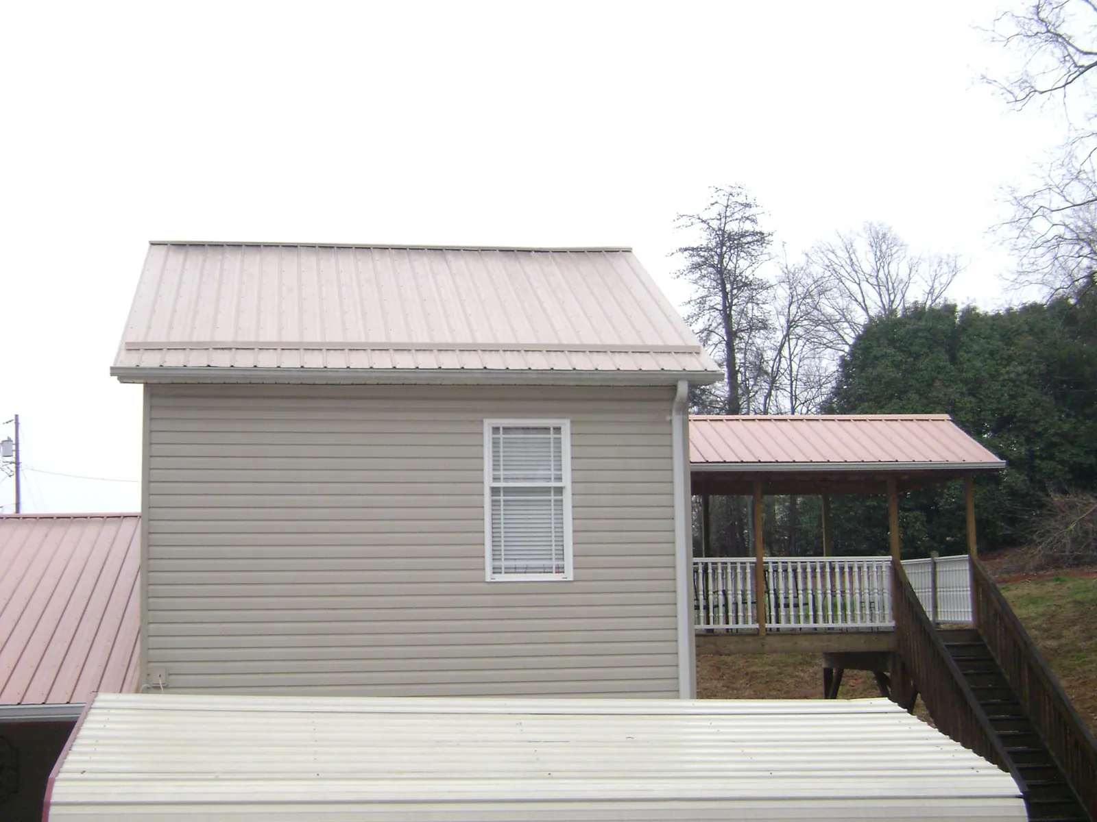 Tan metal roofs on a two story addition and attached porch, from a Roof Replacement job in Winona