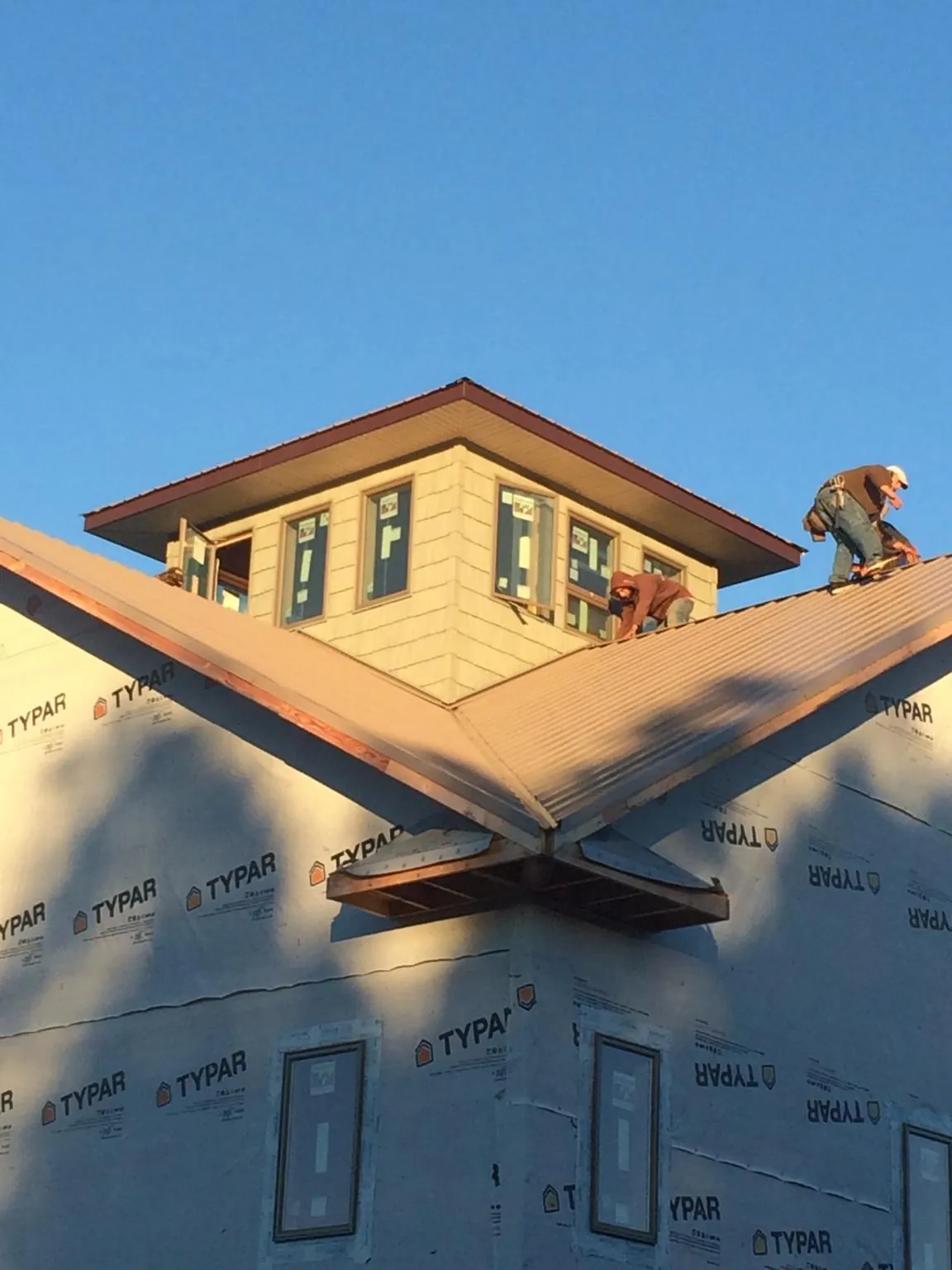 Roofers working around a rooftop cupola on a new metal roof at sunset — Roof Waterproofing in Winona by Roofing Brothers